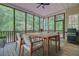 The screened porch features wood flooring, a dining table, a grill and a view of the surrounding greenery at 1851 Oleander Ct, Charleston, SC 29414