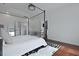 Bright bedroom featuring white walls, wood floors, tray ceiling, and a four-poster bed with black frame at 2141 Sandy Point Ln, Mount Pleasant, SC 29466