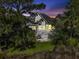Twilight image of the home's backyard featuring a deck, lush landscaping, and exterior lighting at 2141 Sandy Point Ln, Mount Pleasant, SC 29466