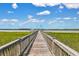 Scenic view of a wooden pier stretching out over the marsh toward the water under a bright blue sky at 2141 Sandy Point Ln, Mount Pleasant, SC 29466