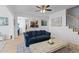 Bright living room with blue sofa, wood floors, ceiling fan and open layout to kitchen and stairway at 2184 Tall Grass Cir, Mount Pleasant, SC 29466