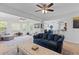 Bright living room with blue sofa, wood floors, ceiling fans and open layout to kitchen and entry at 2184 Tall Grass Cir, Mount Pleasant, SC 29466