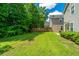 A spacious backyard with lush green grass, mature trees, and view of the home's exterior at 286 Chemistry Cir, Ladson, SC 29456