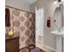 Bathroom features a pedestal sink and shower with patterned curtain. The door is ajar leading to another room at 30 Regency Oaks Dr, Summerville, SC 29485