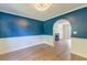 Elegant dining room featuring hardwood floors, a modern blue accent wall, and arched doorway at 3073 Penny Ln, Johns Island, SC 29455