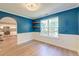 View of a dining room showcasing hardwood floors, blue walls, a window, and an arched doorway leading to the kitchen at 3073 Penny Ln, Johns Island, SC 29455