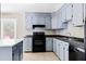 Galley-style kitchen featuring black appliances, light-blue cabinetry, and tile floors at 315 Elliott Dr, Ladson, SC 29456