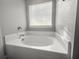 Elegant soaking tub in bathroom with tile surround and natural light at 402 Equinox Cir, Ladson, SC 29456
