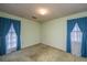 Empty bedroom with large windows with teal curtains and tan carpet at 4328 Cheviot Dr, North Charleston, SC 29418