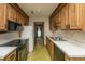 Galley kitchen features wood cabinets, and black appliances adjacent to a doorway leading into another room at 4328 Cheviot Dr, North Charleston, SC 29418