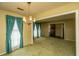 Bright living room features a vintage chandelier, doorway to foyer, and large windows with teal curtains at 4328 Cheviot Dr, North Charleston, SC 29418