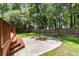 Picturesque backyard featuring a stone firepit, lush greenery, mature trees, and a wood privacy fence at 8166 Scottswood Dr, North Charleston, SC 29418