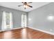 Light-filled bedroom with hardwood floors, two windows with sheer curtains and ceiling fan at 8166 Scottswood Dr, North Charleston, SC 29418