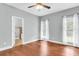 Spacious bedroom with hardwood floors and two windows with sheer curtains, next to ensuite bathroom at 8166 Scottswood Dr, North Charleston, SC 29418