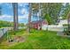 Spacious backyard featuring a red shed with garage door, white picket fence, and lush green grass at 8965 N Red Maple Cir, Summerville, SC 29485