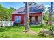 View of the backyard with green grass, a red house, a white picket fence, and trees providing shade at 8965 N Red Maple Cir, Summerville, SC 29485