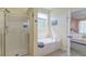 A clean bathroom featuring a walk-in shower, tub, and entry to the Primary bedroom at 8965 N Red Maple Cir, Summerville, SC 29485