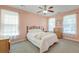 Cozy bedroom with light pink walls, a ceiling fan, a window with white curtains, and a queen size bed at 8965 N Red Maple Cir, Summerville, SC 29485
