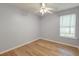 Empty bedroom with light blue walls, hardwood floors, a ceiling fan, and a large window at 8965 N Red Maple Cir, Summerville, SC 29485