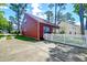 Exterior view of red home featuring well-maintained lawn, white picket fence, and concrete driveway at 8965 N Red Maple Cir, Summerville, SC 29485