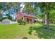 Charming red home with dormer windows, front porch, landscaped yard, and detached garage at 8965 N Red Maple Cir, Summerville, SC 29485