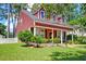 Charming two-story home with red siding, black shutters, and a welcoming front porch at 8965 N Red Maple Cir, Summerville, SC 29485