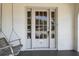 Close-up of the front door with glass panels and a classic design, complemented by a porch swing at 9 Wesley Dr, Charleston, SC 29407