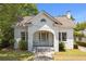 Charming white brick home with arched porch, swing, and manicured landscaping at 9 Wesley Dr, Charleston, SC 29407