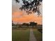 A picturesque backyard featuring a lush green lawn, brick pathway, and a stunning sunset, perfect for outdoor enjoyment at 932 N Shem Dr, Mount Pleasant, SC 29464