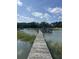Scenic waterfront view showcasing a private wooden dock and pier with a charming seating area under a cloudy sky at 932 N Shem Dr, Mount Pleasant, SC 29464