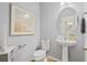 Powder room with pedestal sink, round mirror, gray walls, and artwork, offering a stylish and functional space at 101 Caleb Ct, Ladson, SC 29456