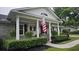 Charming front porch with white columns, an American flag, and manicured hedges enhancing curb appeal at 102 Ashborough Ave, Summerville, SC 29485