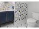Charming powder room featuring a vanity with navy blue cabinets, a patterned wallpaper, and whimsical flower tile flooring at 1055 Royalist Rd, Mount Pleasant, SC 29464