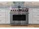 Close up of a state-of-the-art Wolf stainless steel gas range and oven, complete with red knobs and white cabinetry at 1055 Royalist Rd, Mount Pleasant, SC 29464