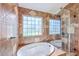 Luxurious bathroom featuring a large soaking tub with glass shower, tile flooring, and natural light at 110 Salinas Ct, Summerville, SC 29483