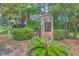 Welcoming neighborhood entrance featuring a brick sign, mature trees, lush landscaping, and inviting homes at 110 Salinas Ct, Summerville, SC 29483