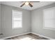 An empty bedroom with gray walls, hardwood floors, a ceiling fan, and two windows at 113 Owens Cir, Summerville, SC 29483
