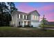 Charming two-story home with black shutters, manicured lawn and attached two car garage at dusk at 1132 Wading Point Blvd, Huger, SC 29450