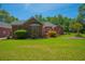 Brick home exterior featuring an expansive green backyard and well-maintained landscaping at 121 Arrowridge Ct, Summerville, SC 29485