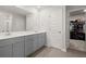 Well-lit bathroom features double sinks with modern grey cabinets and a mirror, with access to the closet at 130 Spotted Way, Summerville, SC 29485