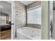 A luxurious soaking tub featuring tile surround, window, and a view of the Primary bedroom at 172 Ashton Dr, Goose Creek, SC 29445