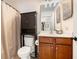 Bathroom featuring a vanity with wood cabinets, black shelving and a toilet with a tan shower curtain at 1723 Indaba Way, Charleston, SC 29414