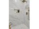 Modern bathroom shower with white marble tile, gold fixtures, and a sleek design at 1730 Harrison Ave, Charleston, SC 29407