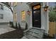 Close-up of a home's exterior featuring a classic black front door, stone steps, and manicured landscaping at 19 Smith St # B, Charleston, SC 29401