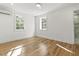 Bright bedroom with hardwood floors, white walls, and two windows letting in natural light at 19 Smith St # C, Charleston, SC 29401