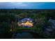 Stunning aerial view of a luxury home nestled among lush greenery, featuring a serene pond and inviting outdoor lighting at 200 Belted Kingfisher Rd, Kiawah Island, SC 29455