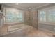 A modern bathroom featuring tiled flooring and glass door walk-in shower and soaker tub at 200 Belted Kingfisher Rd, Kiawah Island, SC 29455