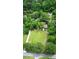 Drone view of a beautiful property showcasing a home, gardens, expansive lawn, and waterfront access at 206 Chaussee Blvd, Summerville, SC 29483