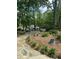 Beautifully landscaped backyard with a stone patio, an outdoor fire pit, mature trees, and lush greenery at 206 Chaussee Blvd, Summerville, SC 29483
