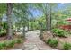 Relaxing backyard with a stone pathway leading to a fire pit area surrounded by lush greenery and mature trees at 206 Chaussee Blvd, Summerville, SC 29483